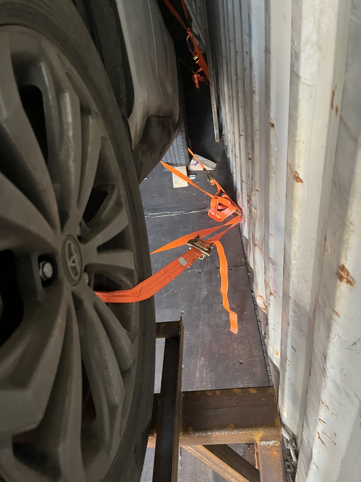 Wheel and tie-down strap detail inside a vehicle shipping container